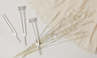 Three tuning forks laid out on a beige background