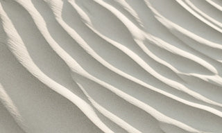 Wave-like ripples in fine sand, echoing the patterns of sound moving through matter