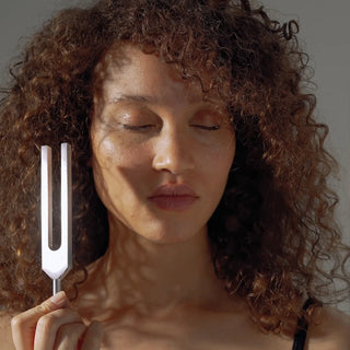 A woman using a 417 Hz Unweighted Tuning Fork for Biofield Tuning sound healing.