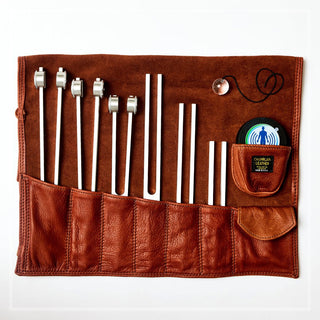 An image of a Biofield Tuning sound healing leather tuning fork storage roll with tuning forks, activator and pedulum.