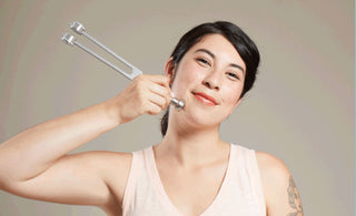 woman uses tuning fork on face for self care