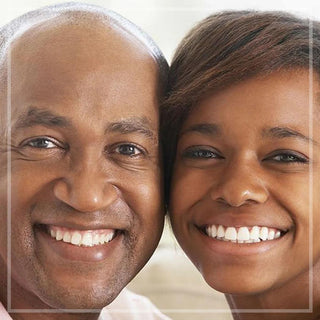 A father and daughter pose together smiling against white backdrop