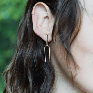 Model wearing Small Handmade Tuning Fork Earrings in solid brass.