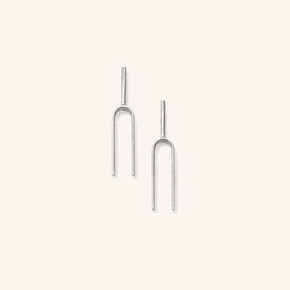 Small Handmade Tuning Fork Earrings in sterling silver on a neutral background.
